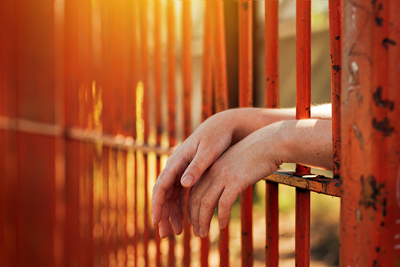 Woman's hands resting on prison bars