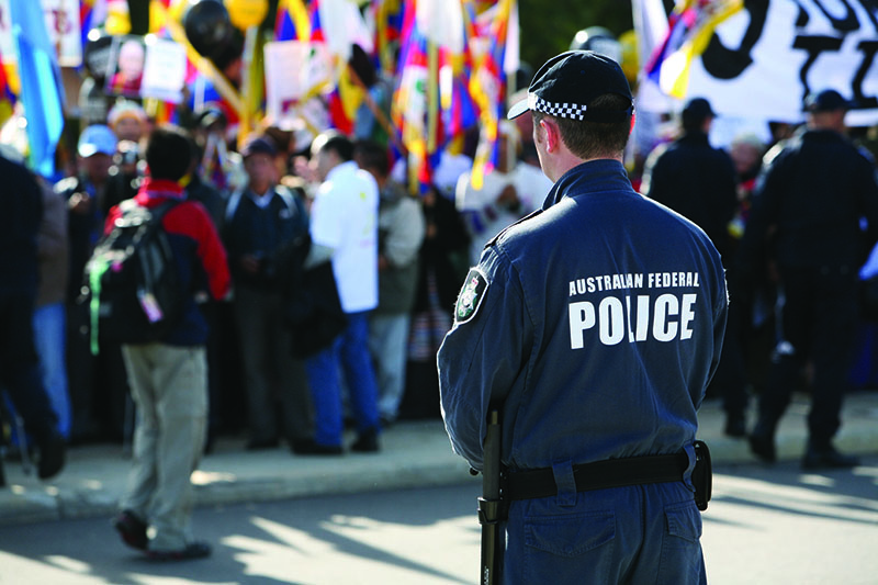 Rear view of an Australian Federal Police officer facing a large crowd at an event