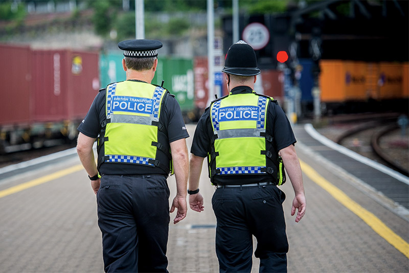 Rear view of BTP officers walking down a train station platform