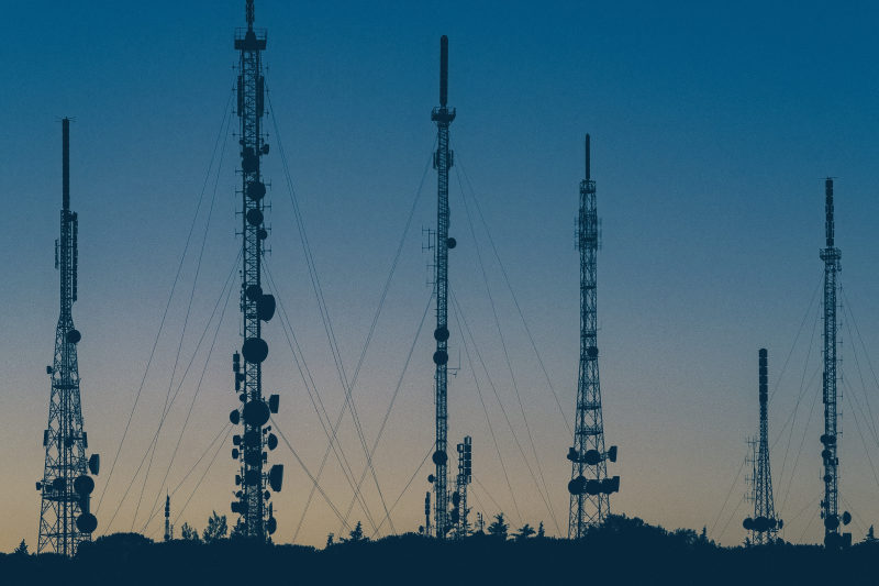 The image features tall communication towers silhouetted against a twilight sky, emphasizing technology's role in facilitating police operations and enhancing communication in law enforcement. - GraphAware