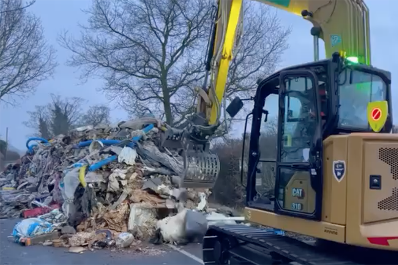 Serious fly tipping being cleared from a road using a digger