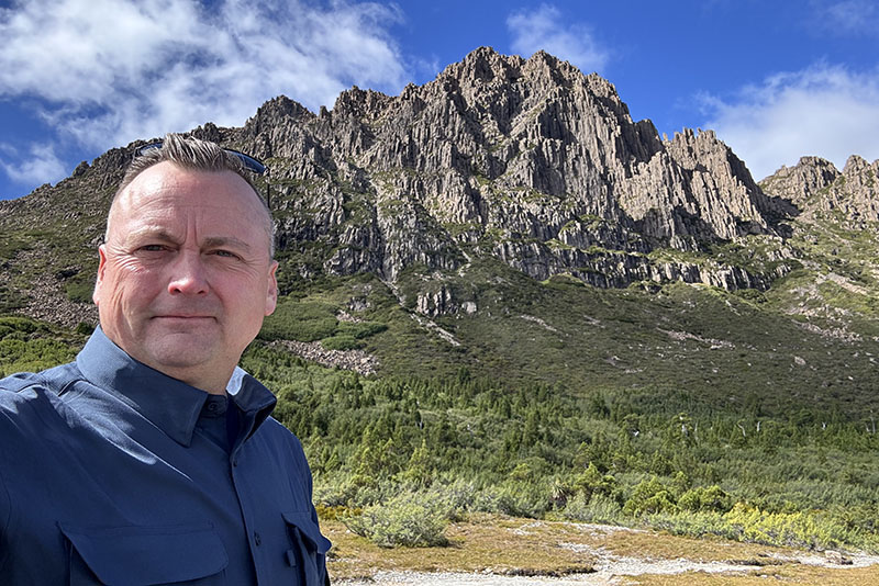 John Kilburn of SAS standing in front of a mountain peak