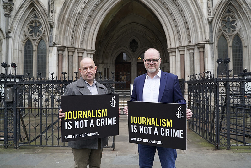 Journalists Barry McCaffrey and Trevor Birney holding Amnesty International placards outside of the court, after a judgement found they were the targets of illegal surveillance by the Police Service of Northern Ireland