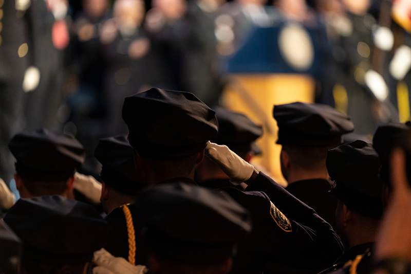 Rear view of officers saluting during New York Police Academy Graduation ceremony at Madison Square Garden