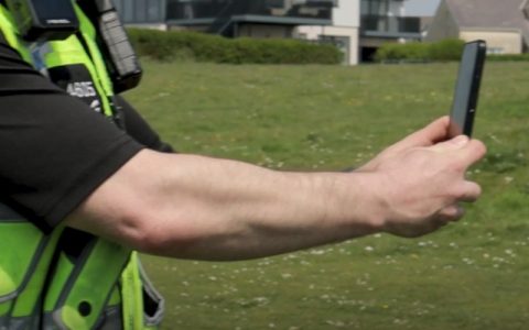 South Wales Police officer holding mobile phone, using operator-initiated facial recognition