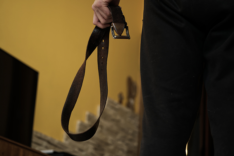 Man standing in a living room, holding a belt