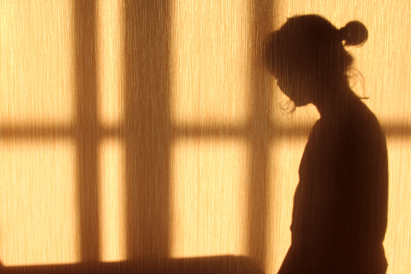 The shadow of a young woman shot against a yellow wall in profile, suggesting victim of domestic abuse, VAWG or sexual offences