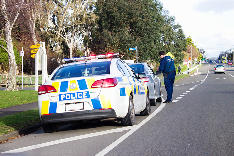 New Zealand Police officer speaks to car driver after stopping vehicle at the side of the road
