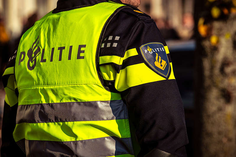 A Dutch police officer seen from behind in uniform with a visible logo