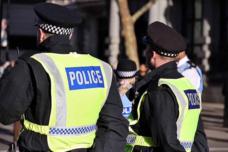Rear view of two officers in uniform and hi vis mentoring an event or on patrol