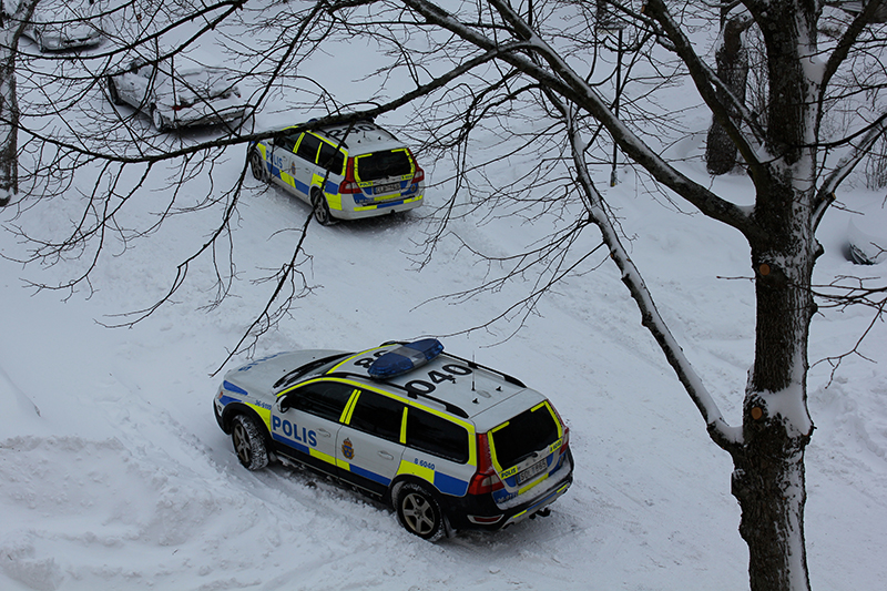 Two swedish police cars parked on a snow filled street outside stockholm during winter.