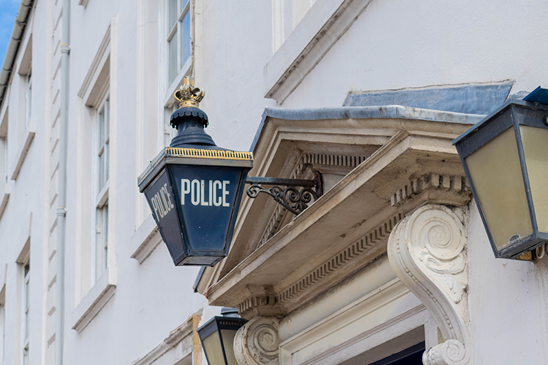 The image features a traditional police sign hanging above a doorway, symbolizing law enforcement and community safety, prominently displayed on a classic building exterior.