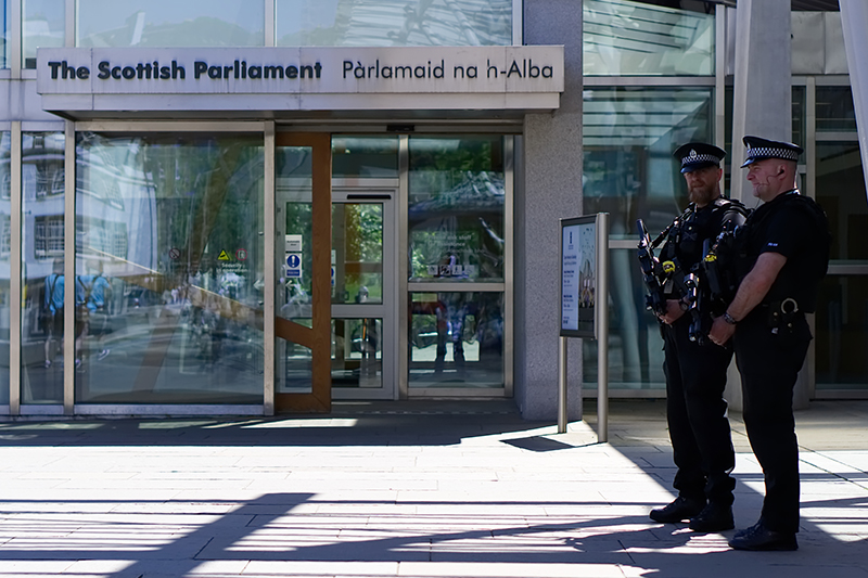 Two policemen on guard outside the Scottish Parliament in bright sunshine during special event.