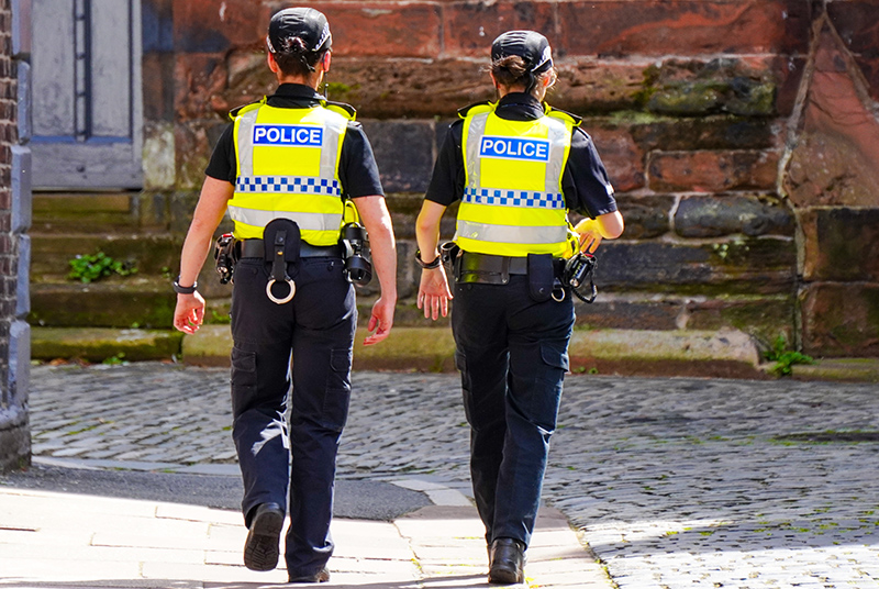 Two UK policewomen walk the beat, pictured from behind