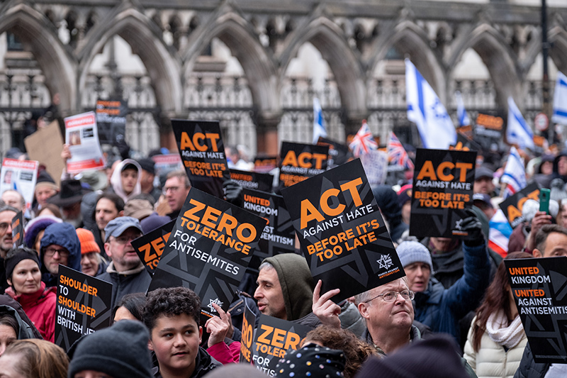 Crowds holding banners and flags aloft, at the March Against Antisemitism,