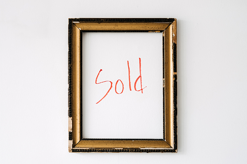 Empty picture frame with red text sold inside.
