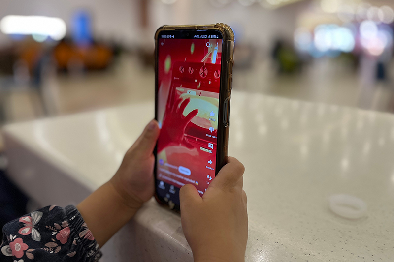 A child (hands only in the picture) focused on watching YouTube on a smartphone