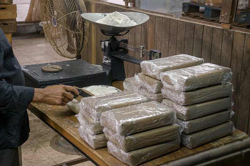 Close up of man s hand weighing out large quantity of cocaine in a cocaine warehouse