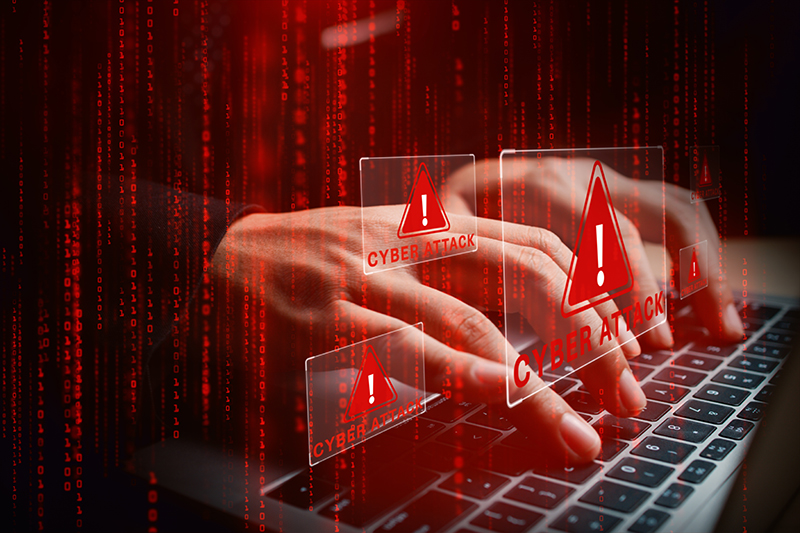 Laptop with hands typing amid glowing cyber attack alerts and red binary code,