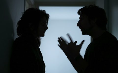 Silhouette of a man and woman (couple) arguing aggressively in a hallway, concept of domestic abuse and family violence