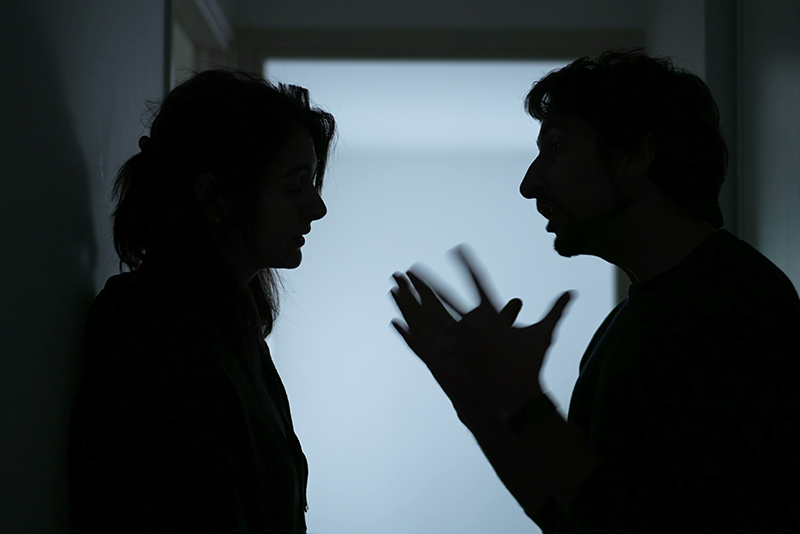 Silhouette of a man and woman (couple) arguing aggressively in a hallway, concept of domestic abuse and family violence