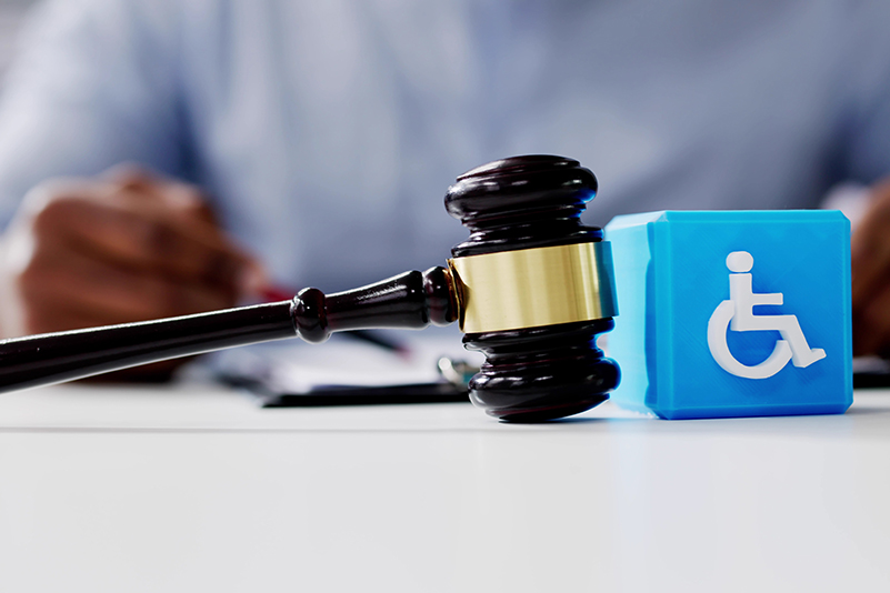 Judges gavel beside disability sign of person in a wheelchair, highlighting just for people with disabilities