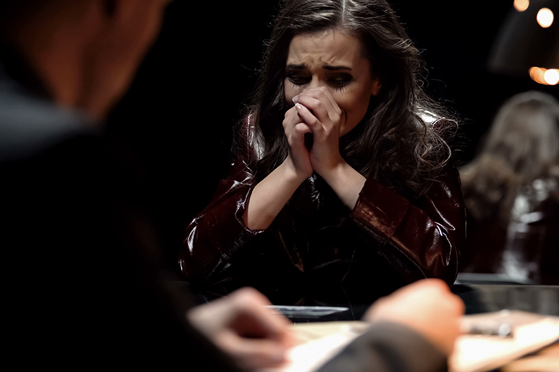 Woman crying, victim being questioned by a detective