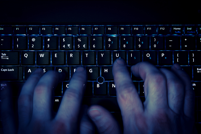 Hands on a computer keyboard signifying cyber crime or dark web