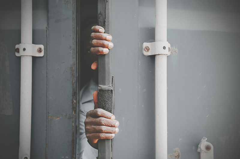 Hands of a stateless black man opening the door of a lorry container, signifying human trafficking