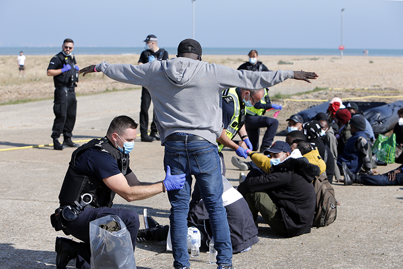 Migrants being questioned and searched by Border Force officials and police on the beach at Dungeness after crossing the English channel to the UK.