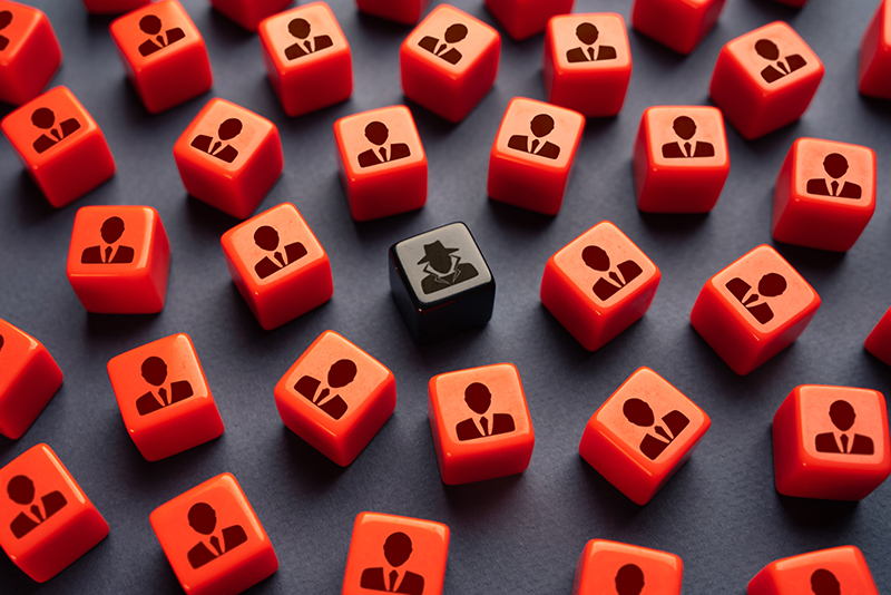 The image features a group of red cubes with a figure symbol, surrounding a single black cube depicting a detective or an insider threat