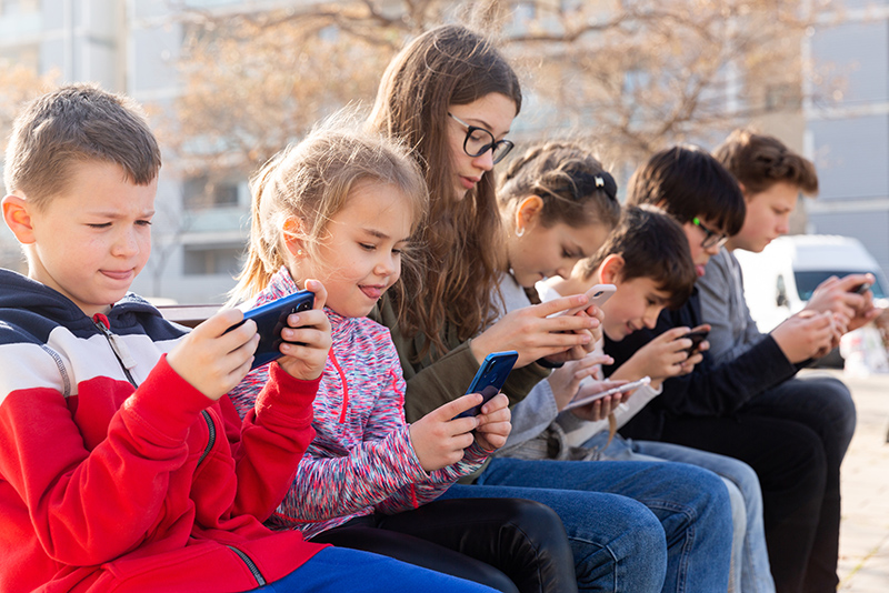 Group of children communicate using smartphones in the playground