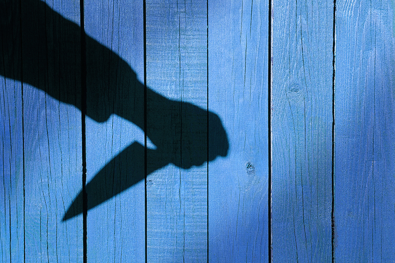 Male Hand Shadow with Kitchen Knife, on natural wooden background.