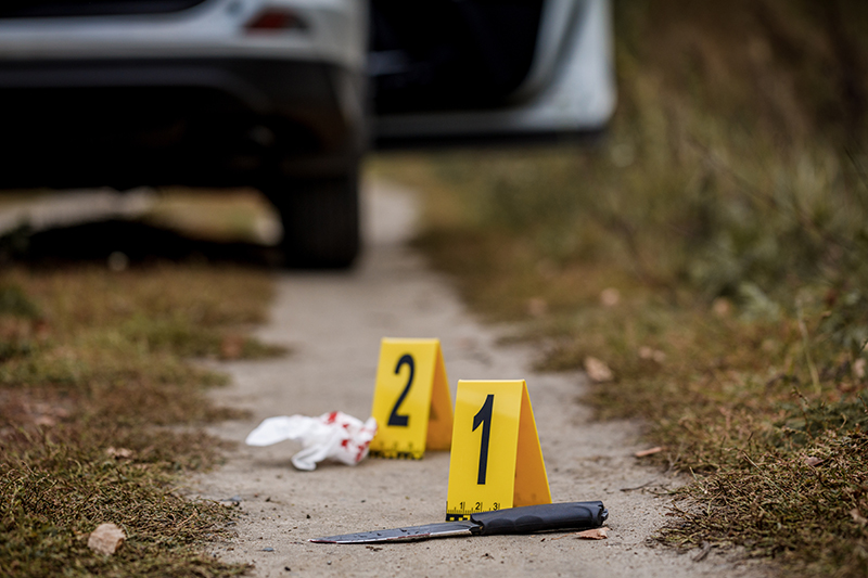 Crime scene investigation, bloody knife with crime markers on the ground, evidence of murder.