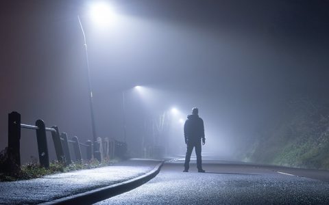 Many standing alone in the road at night