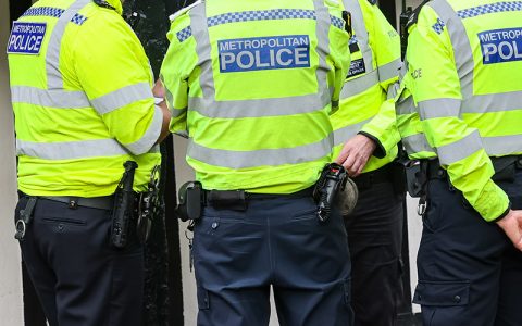 A group of Metropolitan Police officers in bright yellow uniforms are gathered, discussing a situation. Their attire signifies authority and the commitment to public safety in metropolitan areas.