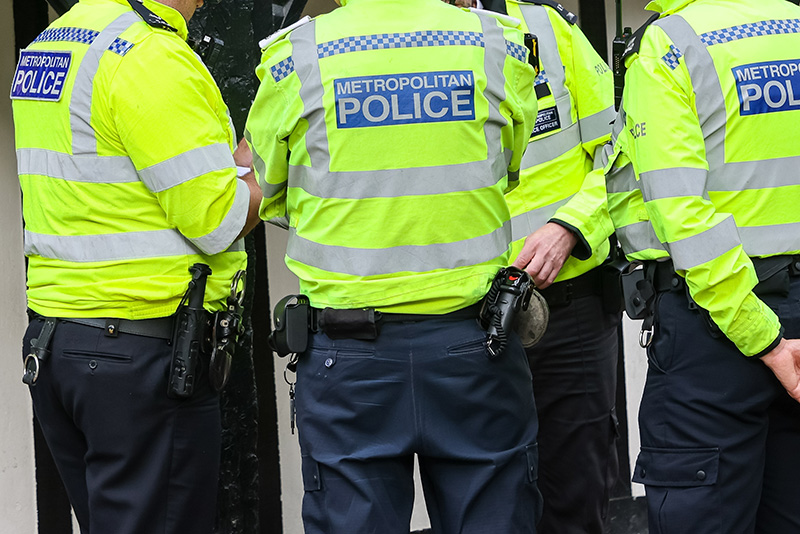A group of Metropolitan Police officers in bright yellow uniforms are gathered, discussing a situation. Their attire signifies authority and the commitment to public safety in metropolitan areas.