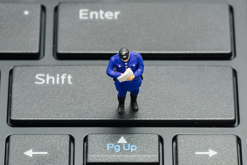 miniature police officer on a keyboard online policing