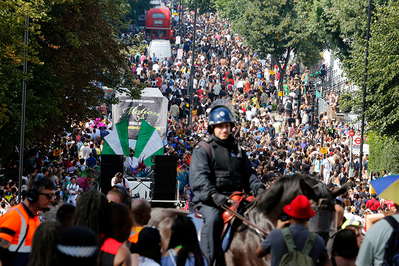 Mounted police officer among the crowds at Ladbroke Grove street with thousand of people at Notting Hill Carnival