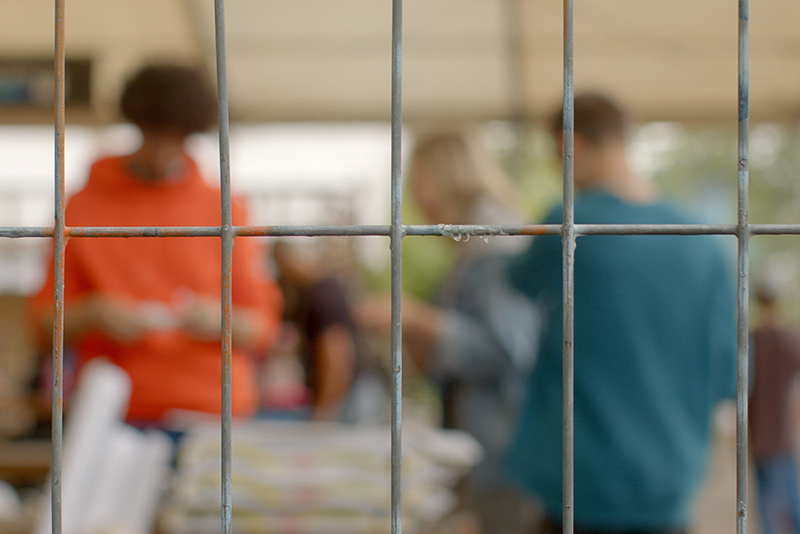 Young offenders in the background (out of focus) behind bars, youth offending