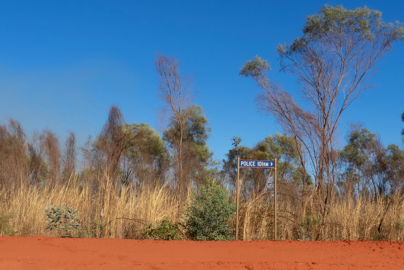 Sign in the Australian outback pointing to next police station 101km away