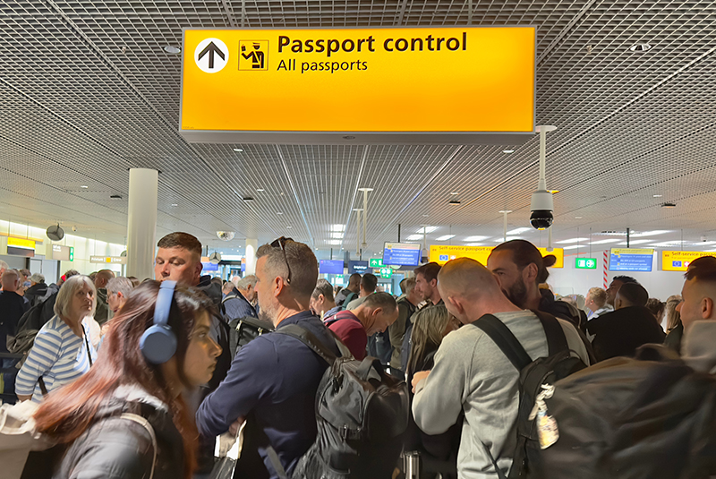 Passengers waiting in line to clear passport control at Amsterdam Schiphol Airport.