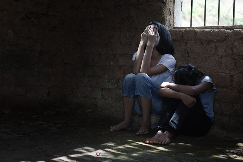Two young victims of human trafficking sit in a cell