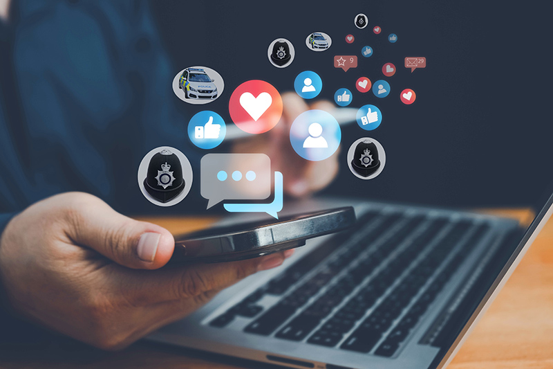 hand holding phone with social media icons rising from the handset, alongside police helmets and cars, suggesting police use of social media