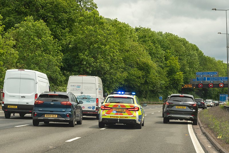 Traffic in the outside lane of the M25 move over to allow a police patrol car to pass through to attend an accident ahead.