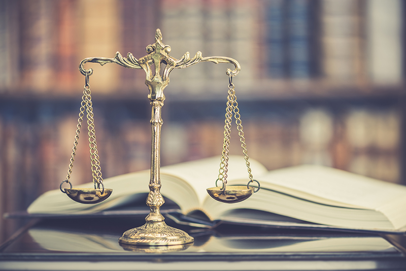 The image features a golden scale of justice balancing over an open law book, symbolizing fairness and the legal system's pursuit of truth and equity in policing.