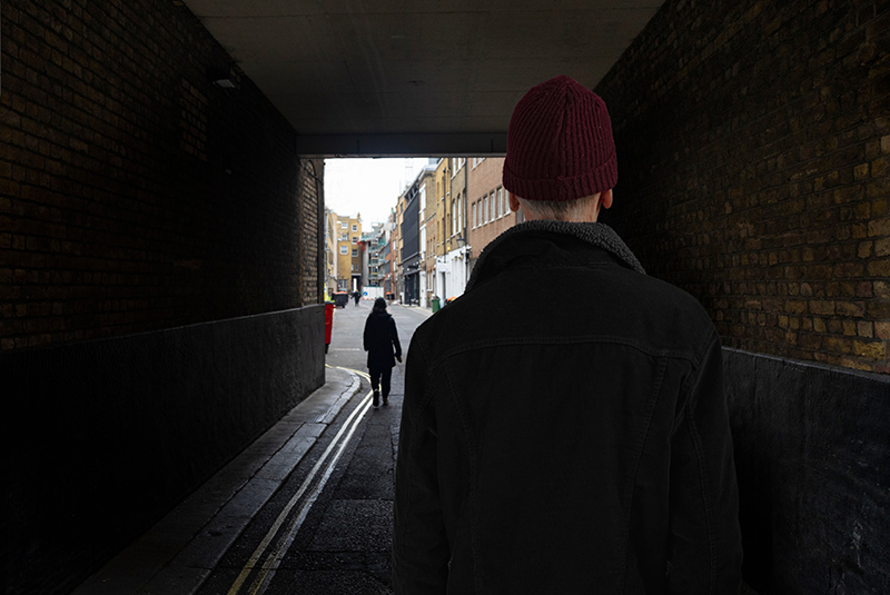 Back view of man following women under bridge stalker sex offender