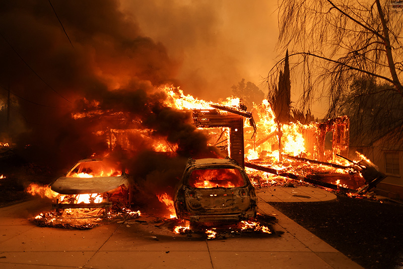 cars and house burning as a result of wildfires in Los Angeles