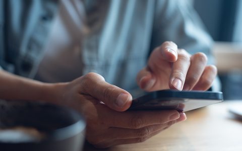 close up of woman's hands scrolling through a mobile phone