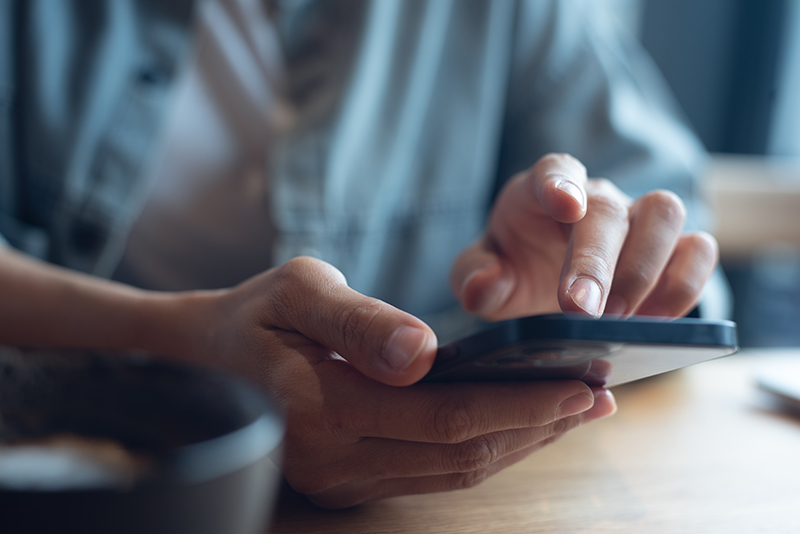 close up of woman's hands scrolling through a mobile phone